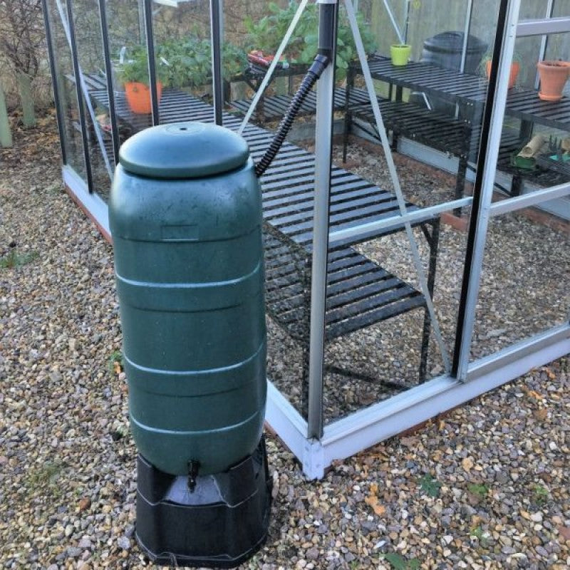 Vitavia 100L water butt with stand, tap and downpipe connector beside a greenhouse