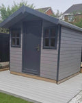Suresheds Ingleton Lodge composite garden building with apex roof, solid anthracite uPVC door and two four-pane Georgian windows, on a composite deck