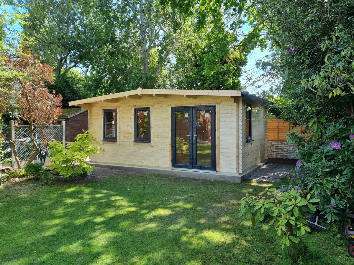Log cabin garden office with anthracite doors in a sunny garden